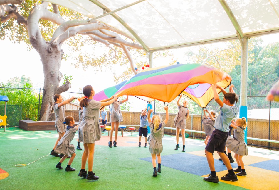 Primary school children gather around a parachute for play.